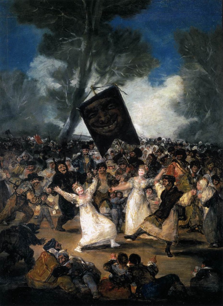 A dense masked carnival crowd surges forward as one mass beneath a large banner bearing a grinning face, in a wooded clearing.
